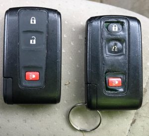 Two keys are sitting next to each other on a car.